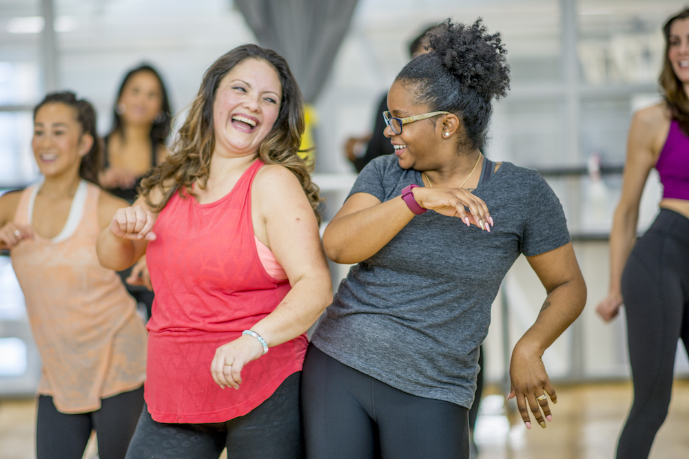 two women in exercise dance class laughing together