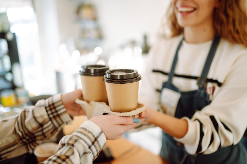 Image shoes female barista giving takeaway coffees to a female customer