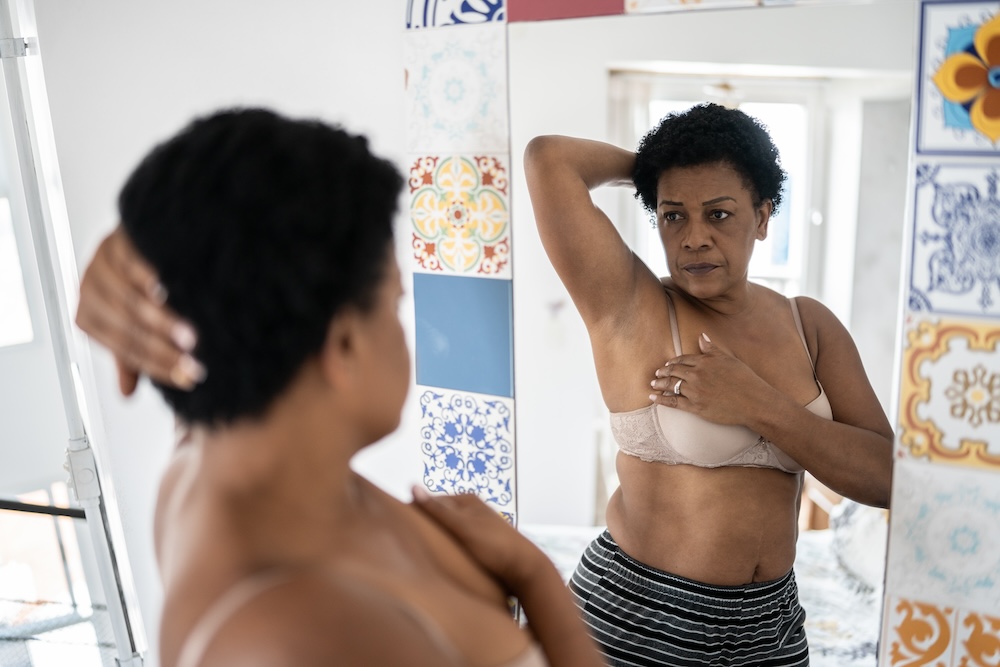 Woman checks herself for breast cancer in mirror