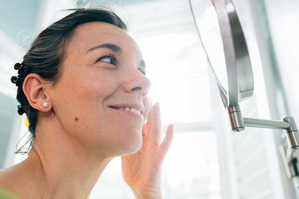 Woman examining facial hair in the mirror