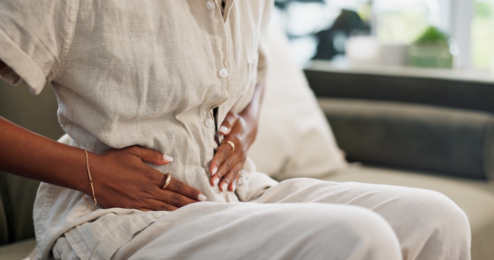 Woman with gut pain sitting and holding her stomach