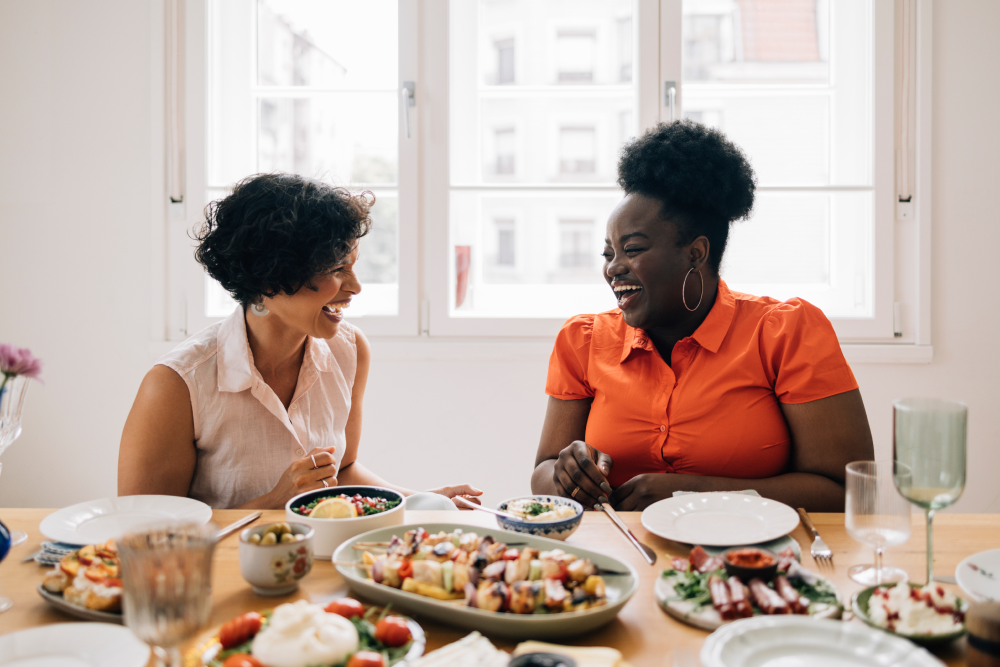 Two women chatting over a spread of healthy food