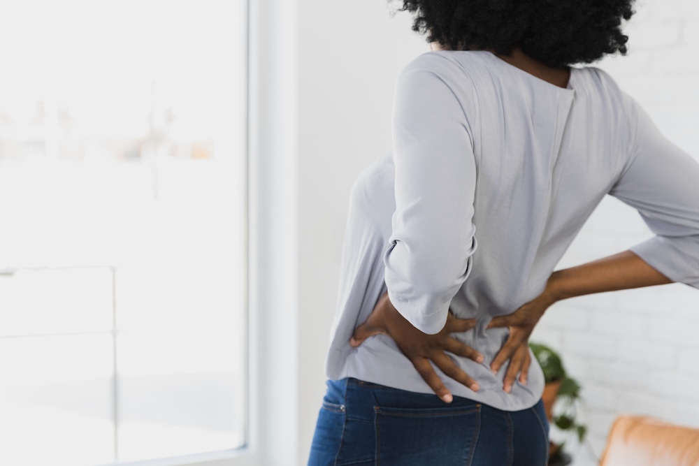 Woman grabs her back in pain and discomfort.