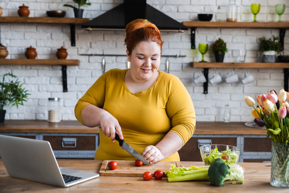 Plus size caucasian woman making a salad in her kitchen