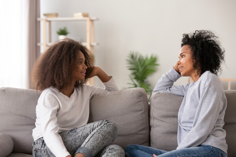 Mother chatting with teen daughter on the couch