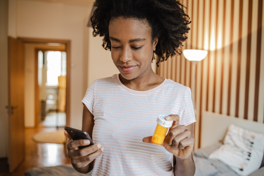 Woman communicating with the doctor online while holding a bottle of medicine in her hand